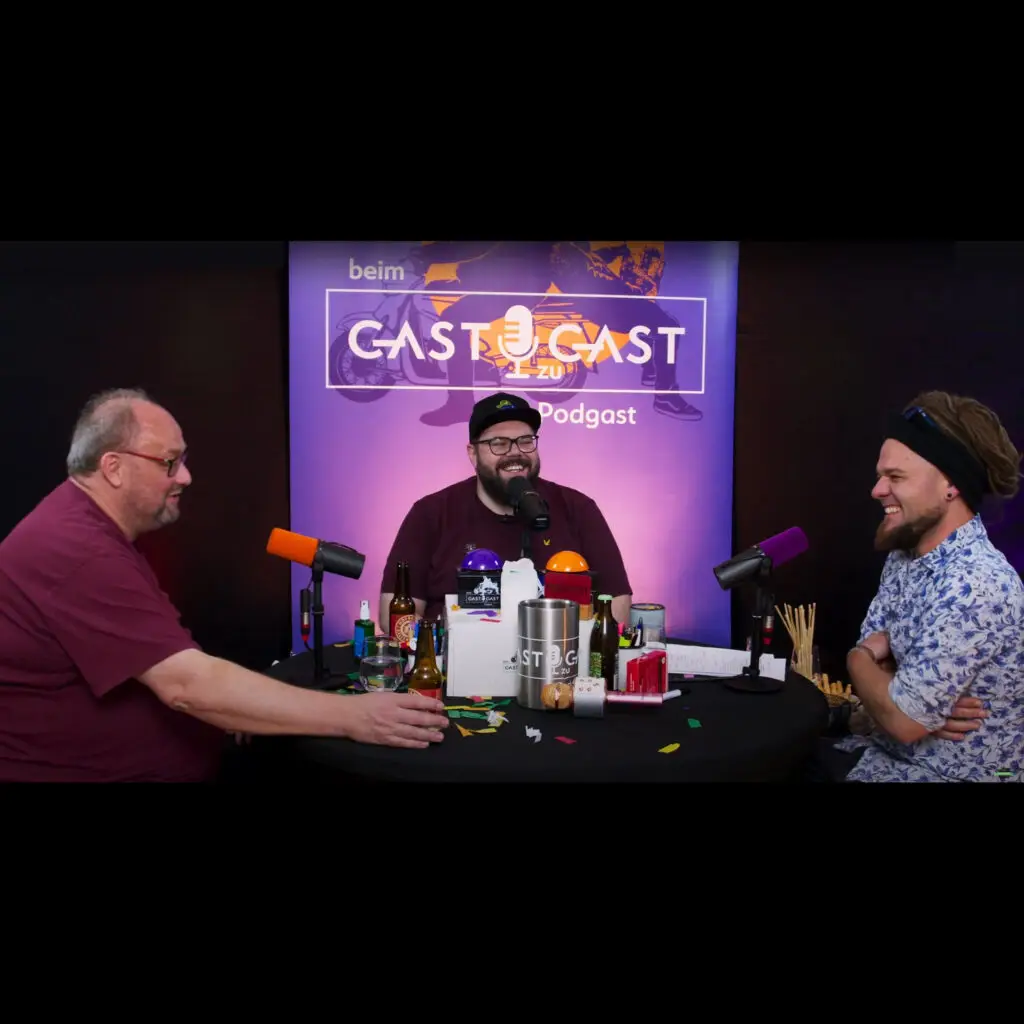 Michael Bauer sitzt zusammen mit Günther Lainer und Christoph "Krauli" Held im Podcast Studio vor drei Mikrofonen